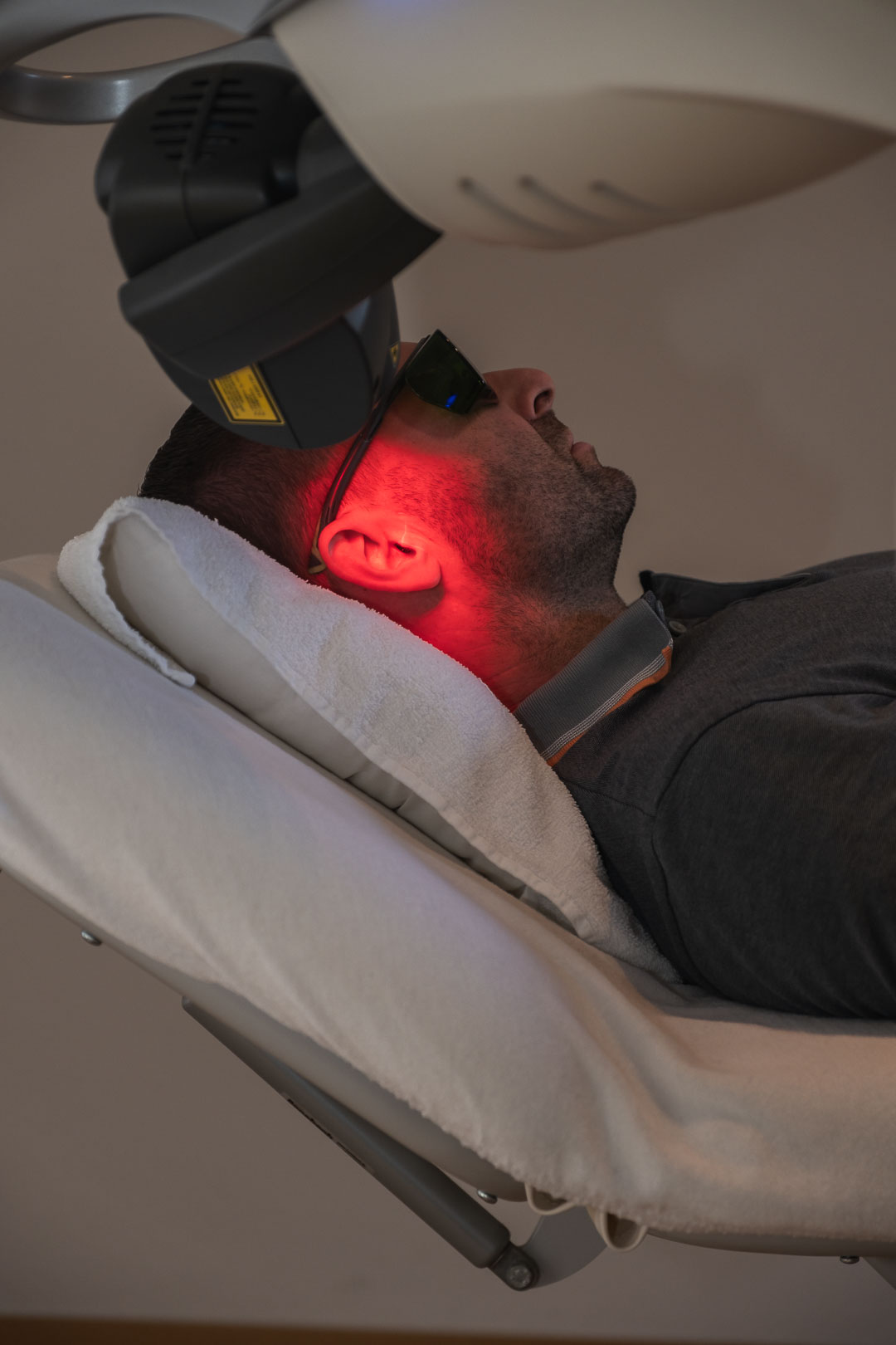 Mann-bei-Lasertherapie Mann bekommt sein Ohr mit Laser bestrahlt